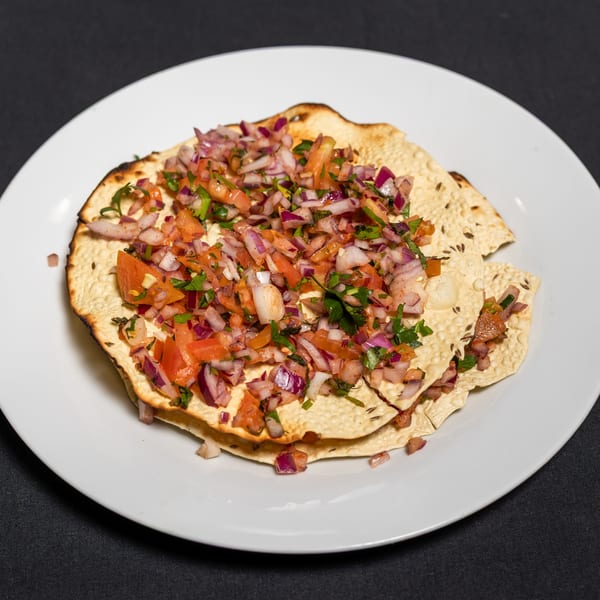 Indian papadum topped with a fresh salsa of diced tomatoes, red onions, and cilantro.