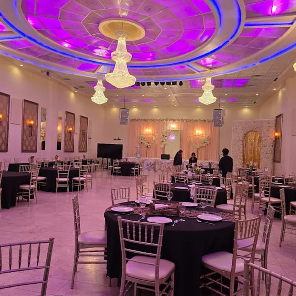Grand Dhaba's large banquet hall with round tables, black tablecloths, and a stage with floral decor.