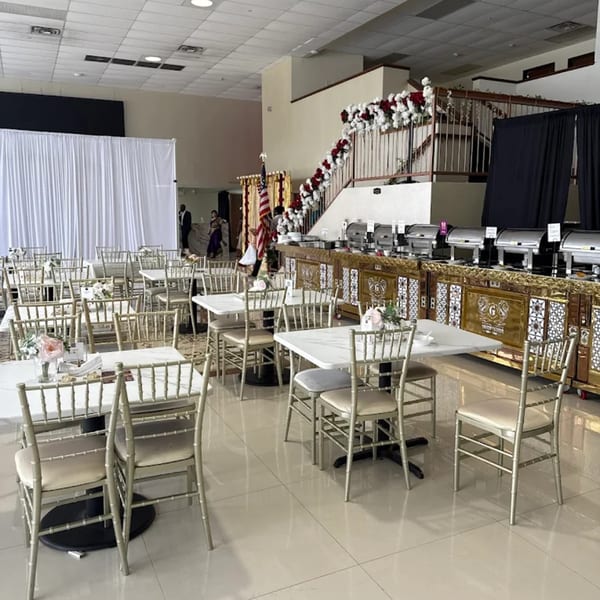 Grand Dhaba's spacious dining area with tables, chairs, a buffet line, and a floral-decorated staircase.