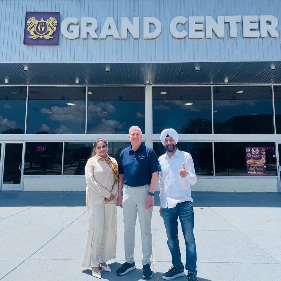Three people, including the Plano Mayor, stand outside Grand Center, home to Grand Dhaba Indian restaurant.