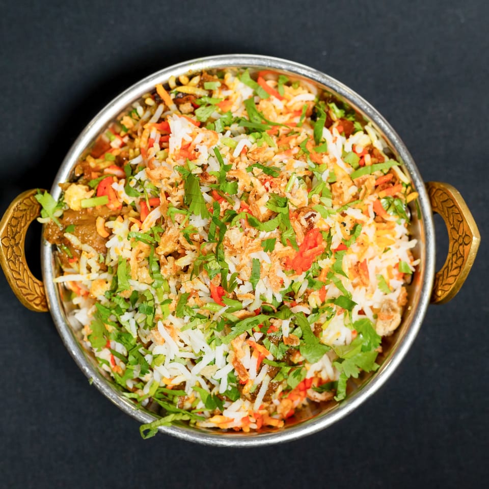 Grand Dhaba's Indian biryani, a flavorful rice dish with meat and spices, served in a metal bowl.